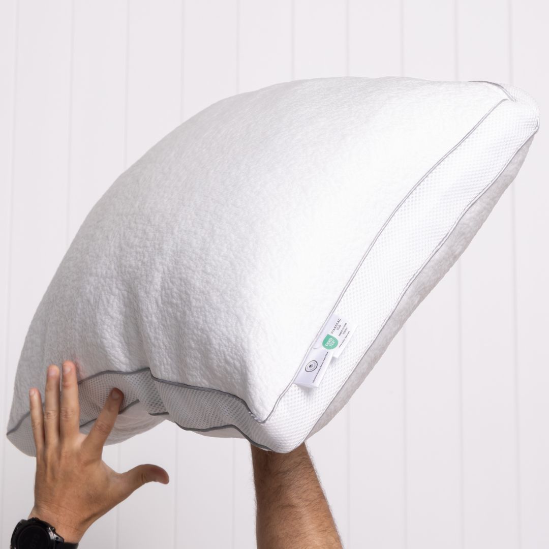 White pillow with a hand touching it against a white background