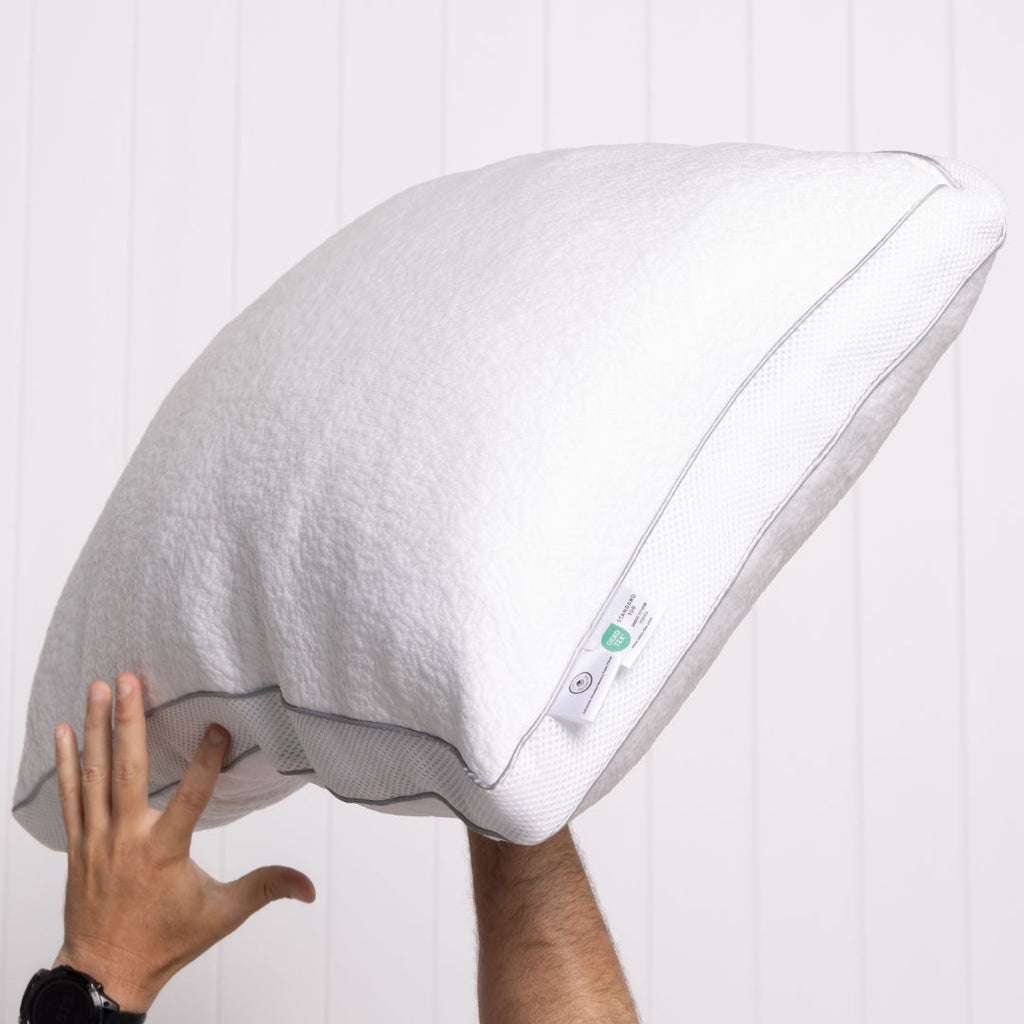 White pillow with a hand touching it against a white background