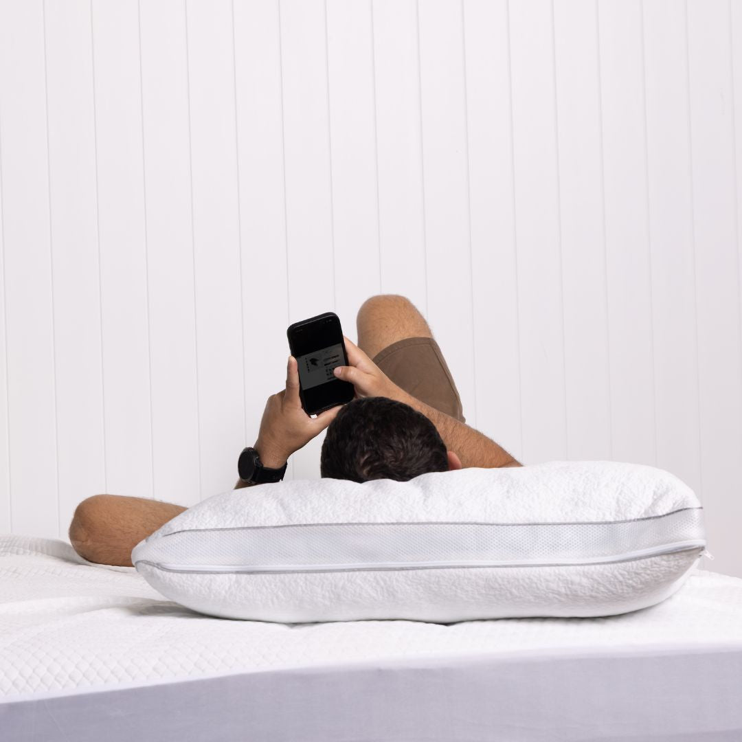 Person using a smartphone on a white pillow against a light background