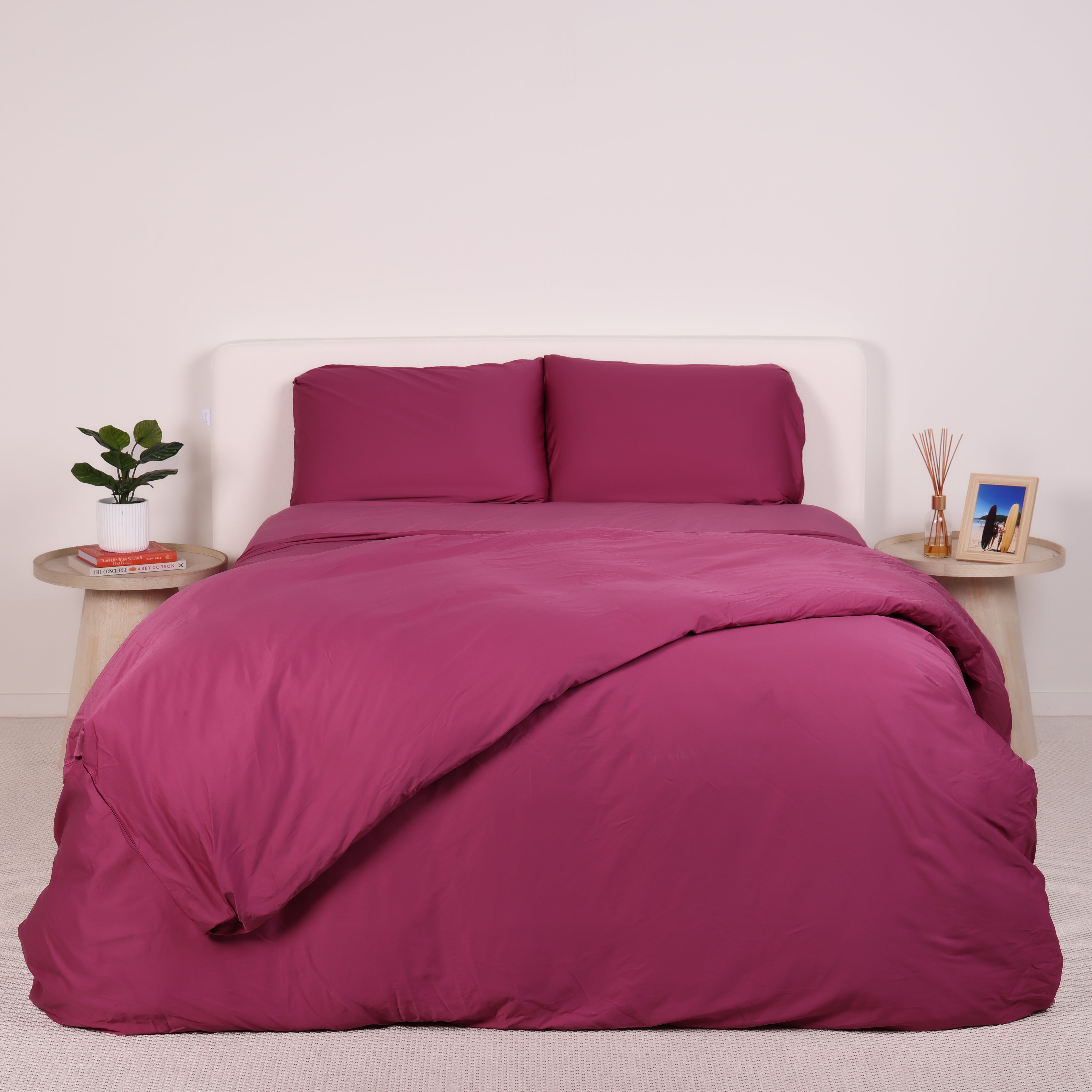 A neatly made bed with grey bedding and two wooden side tables.