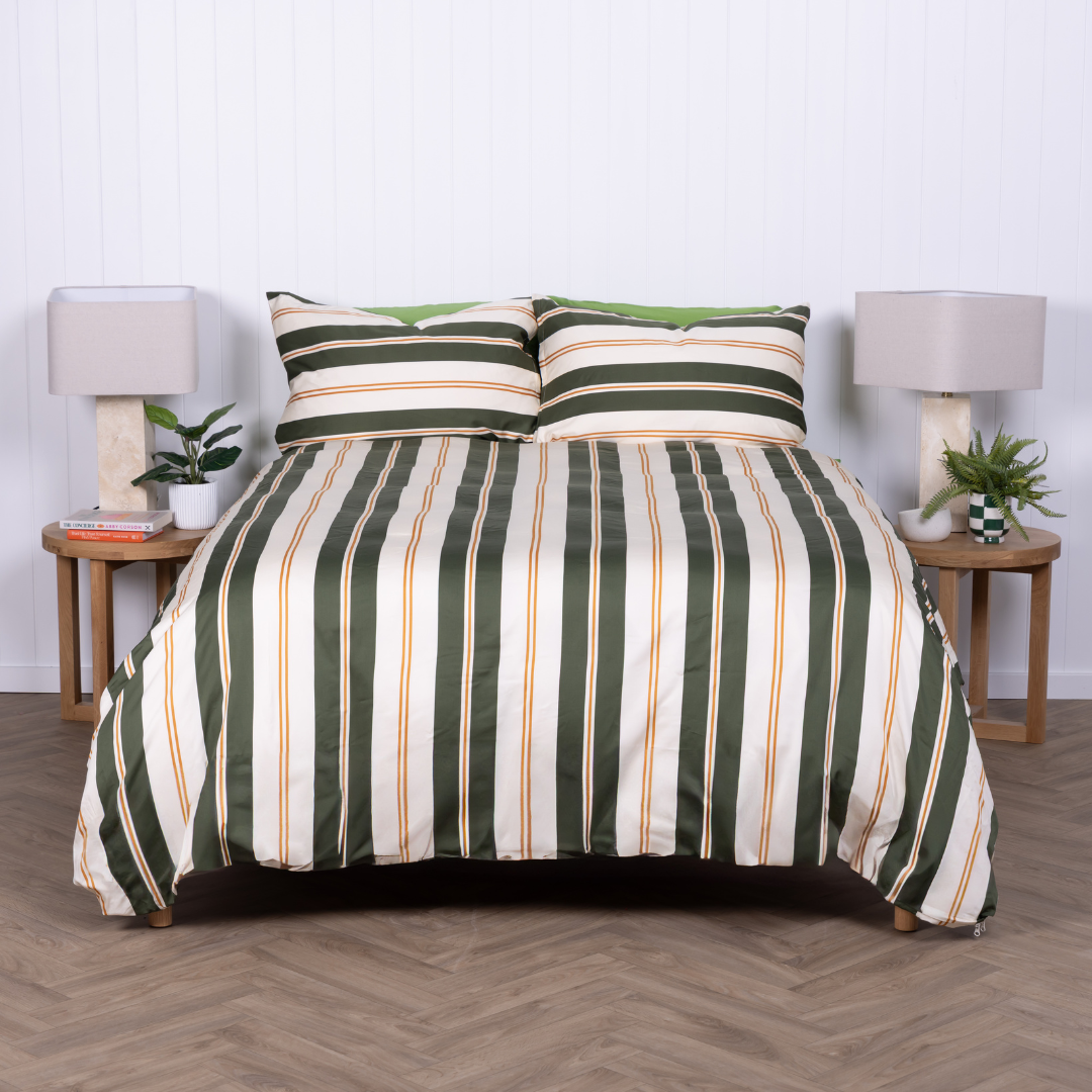 Norfolk bedding set with olive, white, and amber stripes on a made bed.