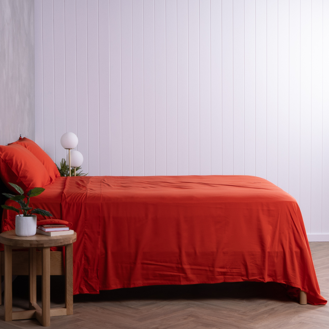 Side angle of bed dressed in red bamboo cotton sheets, highlighting smooth finish and tailored fit.