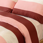 Close-up of matching pillowcases and quilt cover featuring wide blush pink, cream, and burgundy stripes, showcasing the coordinated bedding design and smooth finish.