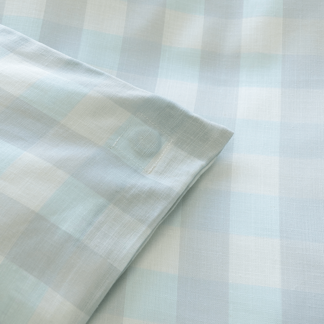 Close-up of a light blue gingham quilt cover corner tie, highlighting the internal attachment detail designed to help keep the quilt insert securely in place