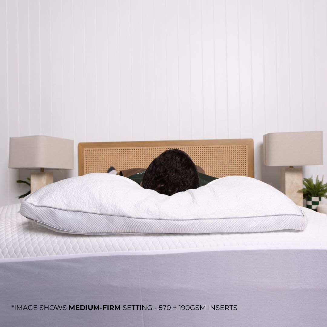 Person lying on a bed with a white pillow and mattress, in a bedroom setting.