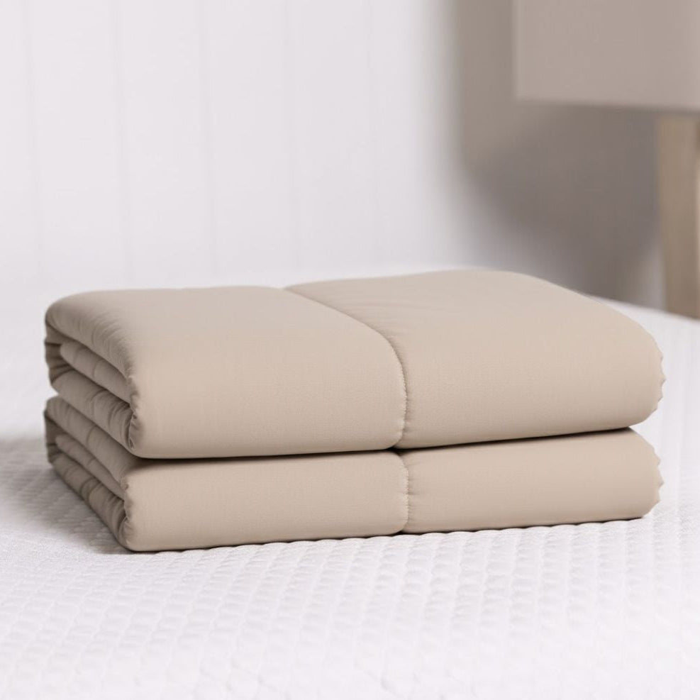 Folded beige cooling blanket on a white bed