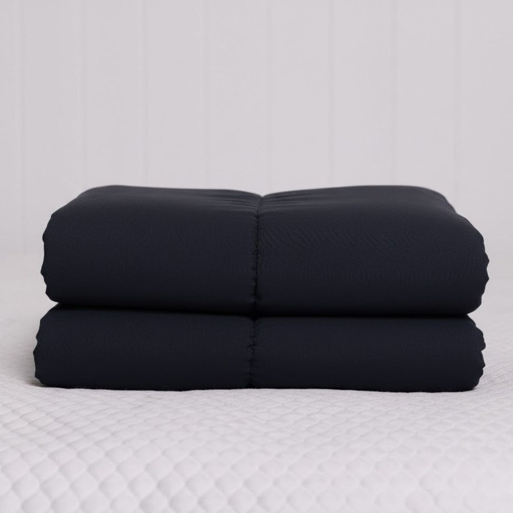 Stack of black cooling blankets on a white surface