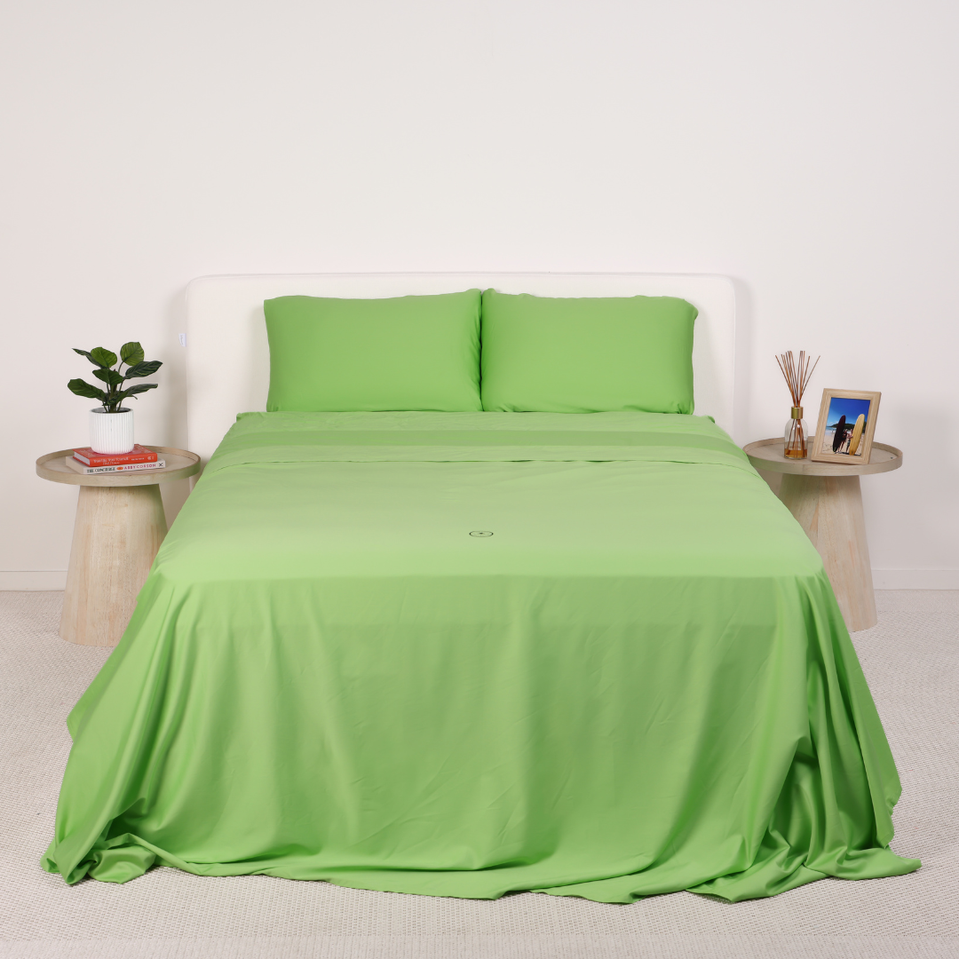 A neatly made bed with grey bedding and two wooden side tables.