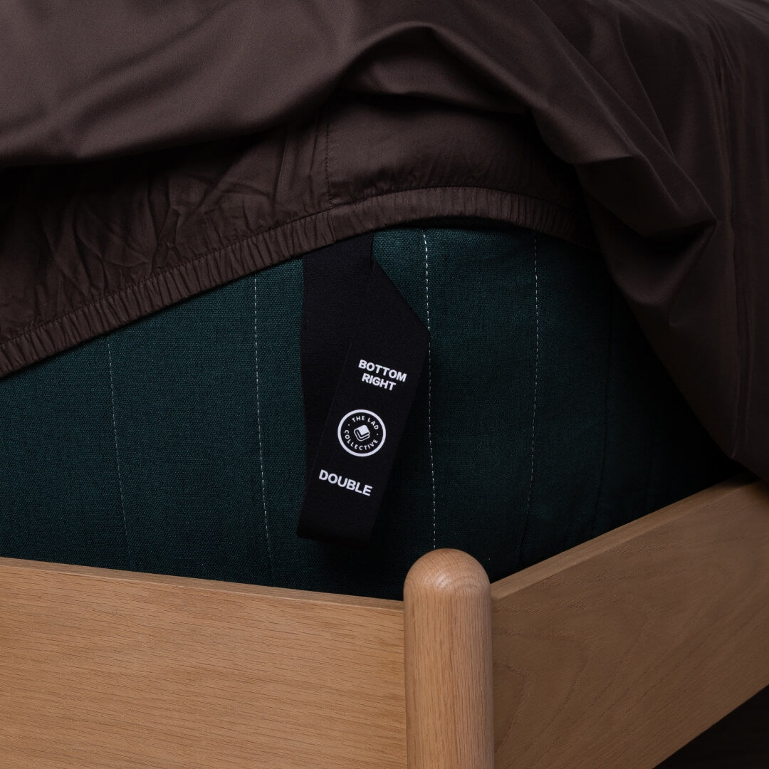 Chocolate brown fitted sheet with a labeled corner strap to show which corner goes where.