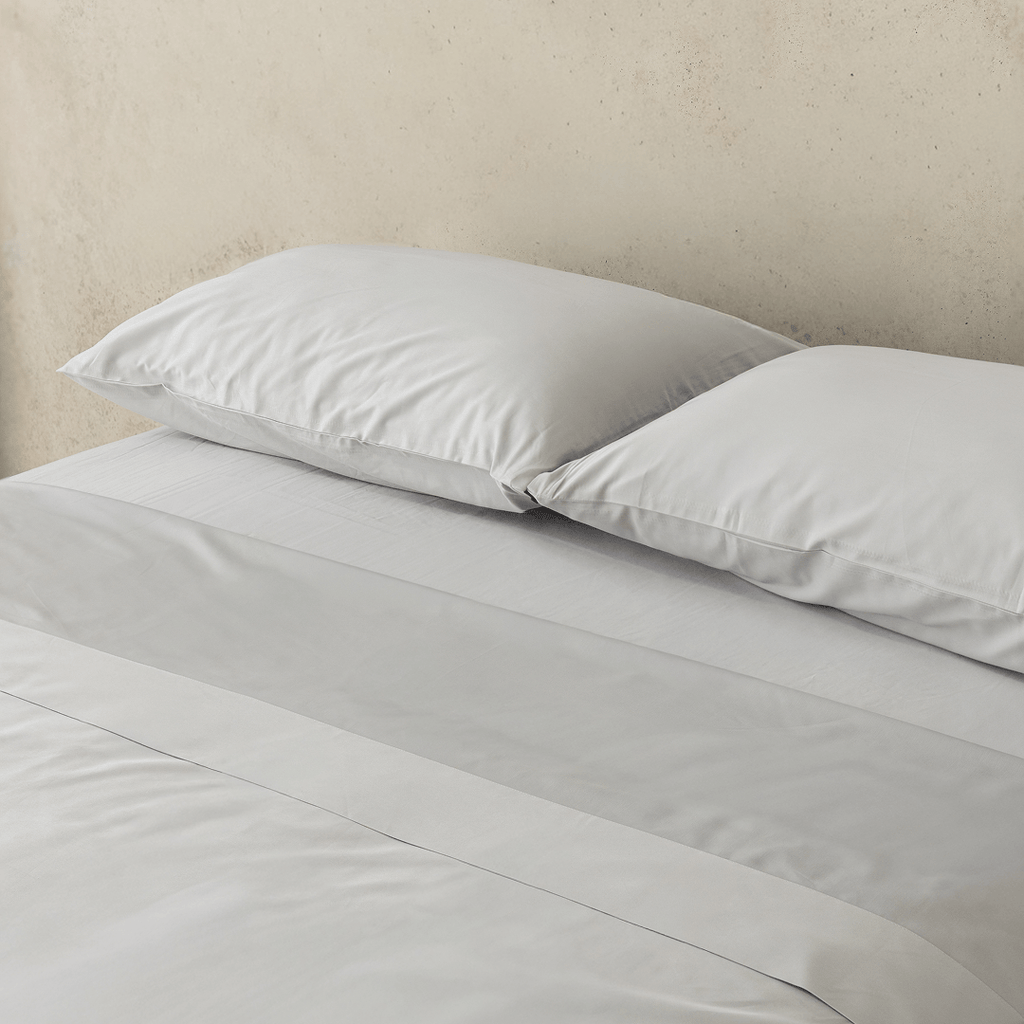 Close-up of two light gray pillows resting on matching sheets, highlighting the smooth fabric and clean finish.