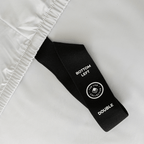 Close-up of a black fitted-sheet corner strap labelled “Bottom Left” and “Double” against light gray bedding.