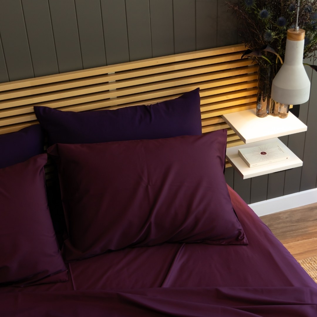 Burgundy pillowcases and bedding set, with deep purple pillowcases in the back of the bed.