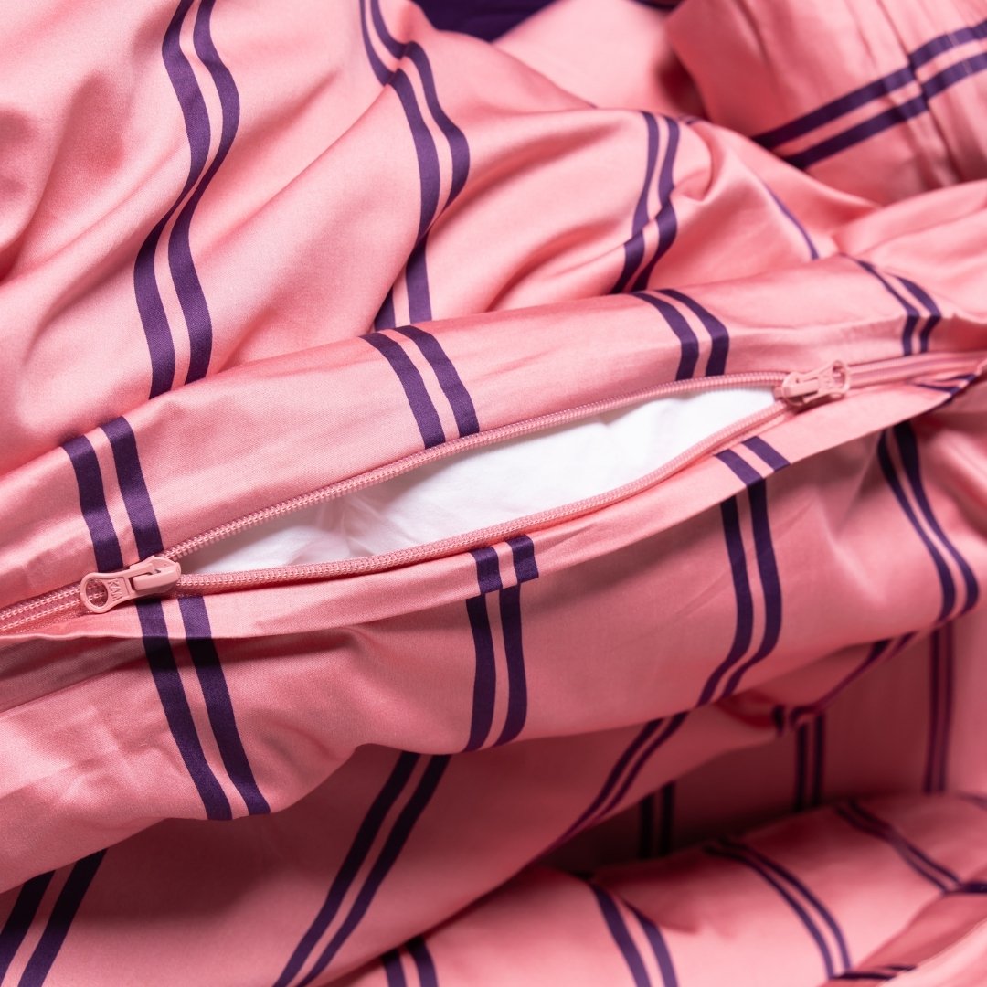 Close-up of a pink quilt cover with purple stripes and a zipper.