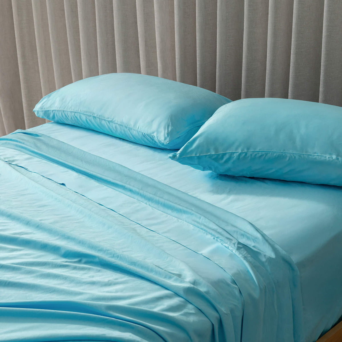 Blue bedding set with pillows on a bed against a neutral headboard.