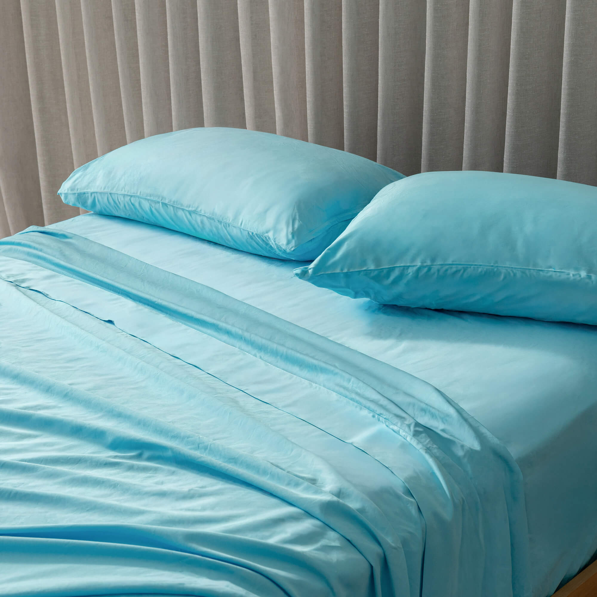 Blue bedding set with pillows on a bed against a neutral headboard.