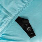 Close-up of a blue fabric with a black labelled loop strap on a light blue background