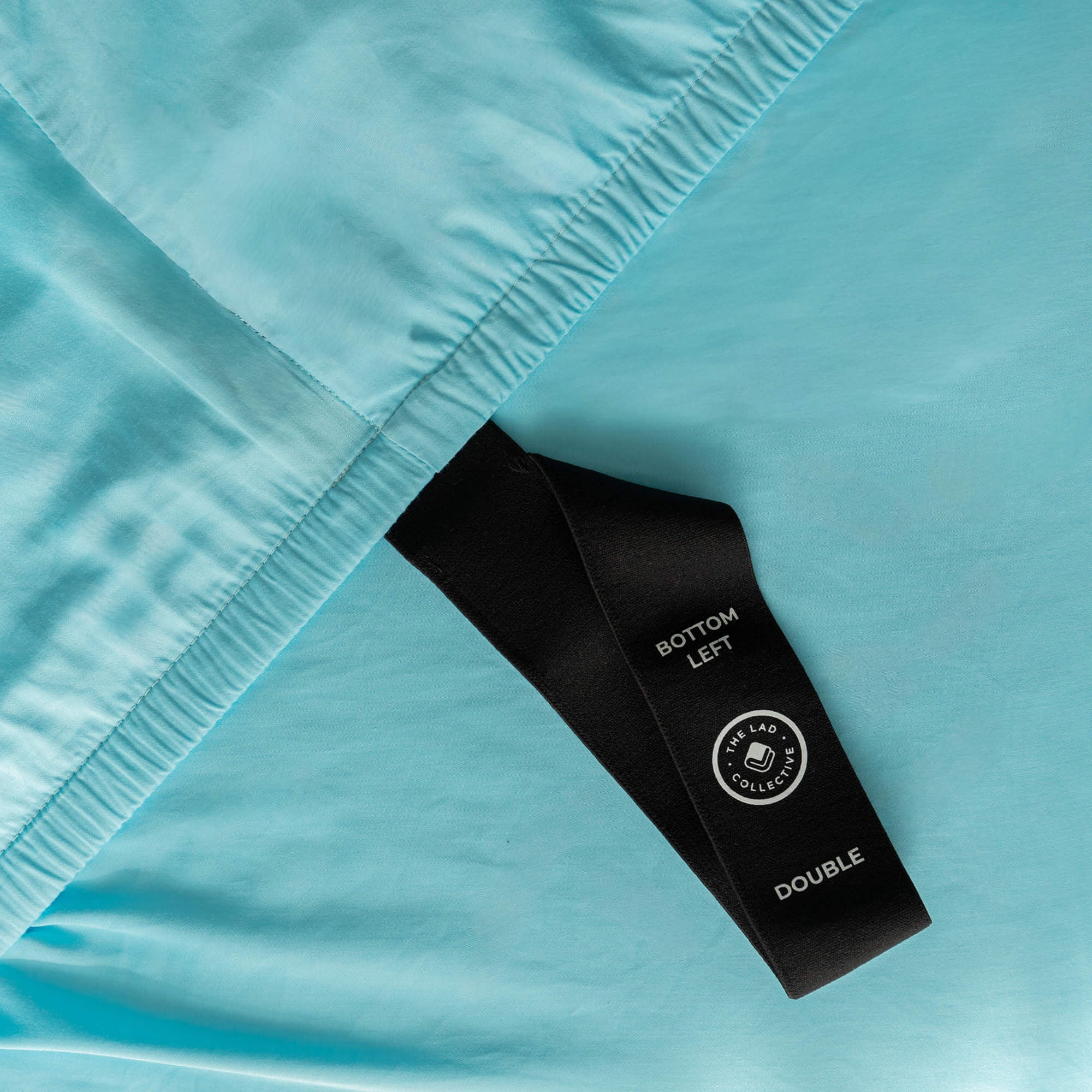 Close-up of a blue fabric with a black labelled loop strap on a light blue background