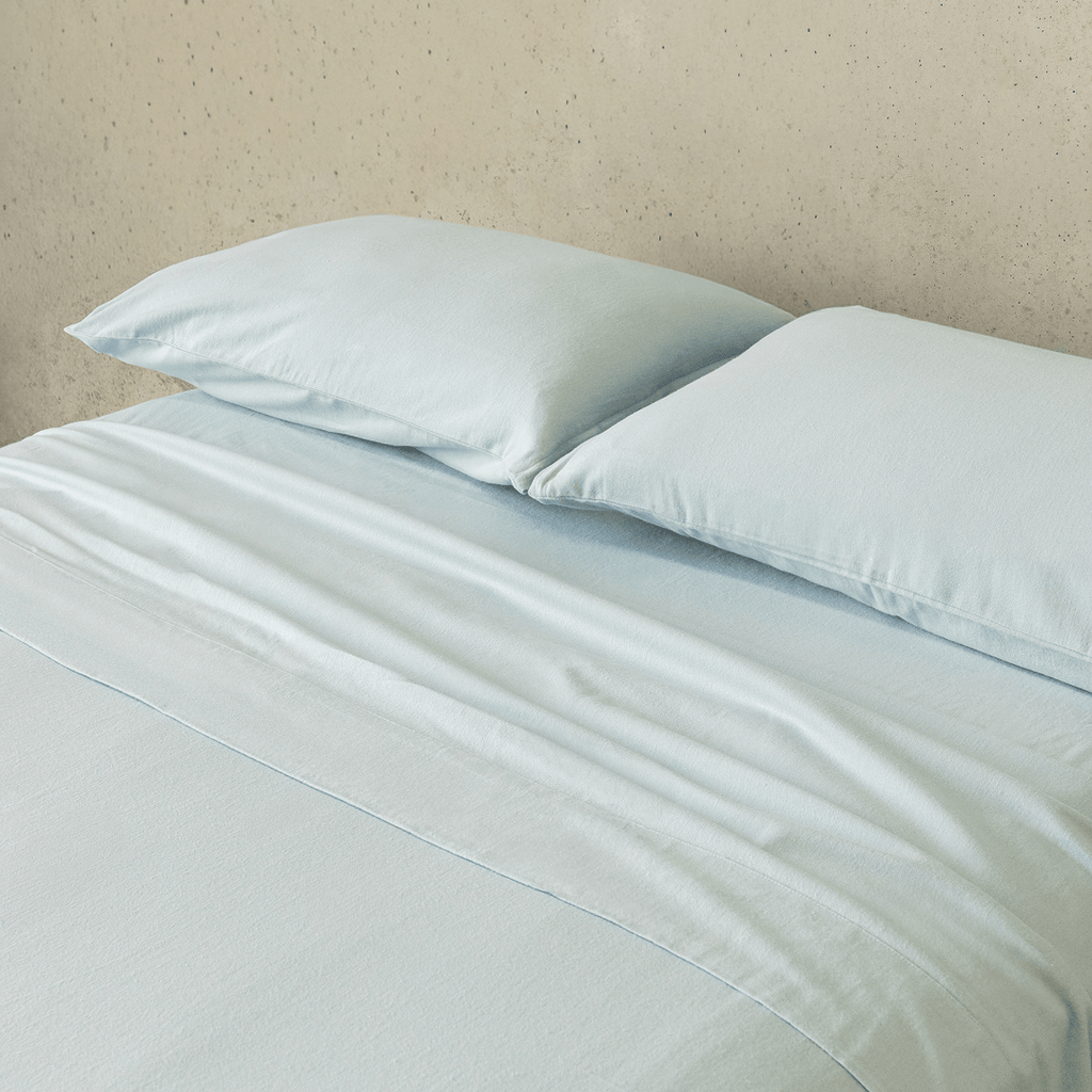 Close-up of a light blue fitted sheet and matching pillowcases, highlighting the smooth texture, soft finish, and coordinated bedding design.