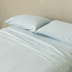 Close-up of a light blue fitted sheet and matching pillowcases, highlighting the smooth texture, soft finish, and coordinated bedding design.