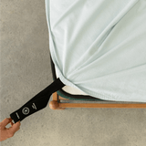 Light blue fitted sheet with an orientation tag pulled from the mattress corner, demonstrating the easy-to-identify labeling system for quick bed setup.