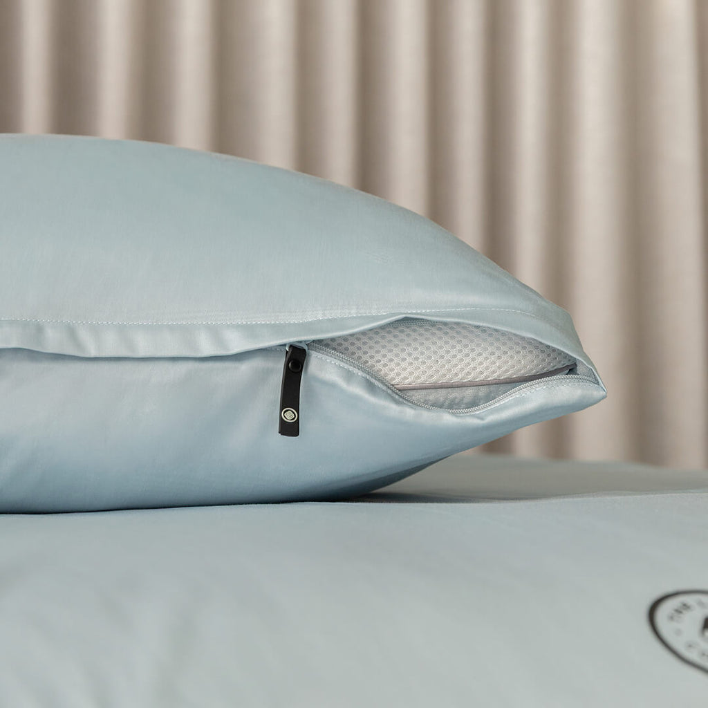 Light blue pillowcase with zipper on a pillow, with a neutral background.