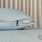Light blue pillowcase with zipper on a pillow, with a neutral background.