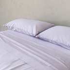 Close-up of two light lavender pillows resting on smooth matching sheets, highlighting the soft fabric and subtle sheen.