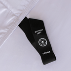 Close-up of a black fitted-sheet corner strap labelled “Bottom Left” and “Double” against light lavender fabric.