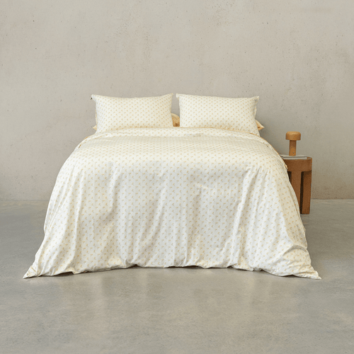 Cream quilt cover set featuring a delicate yellow floral motif made up on a double bed with two matching pillowcases