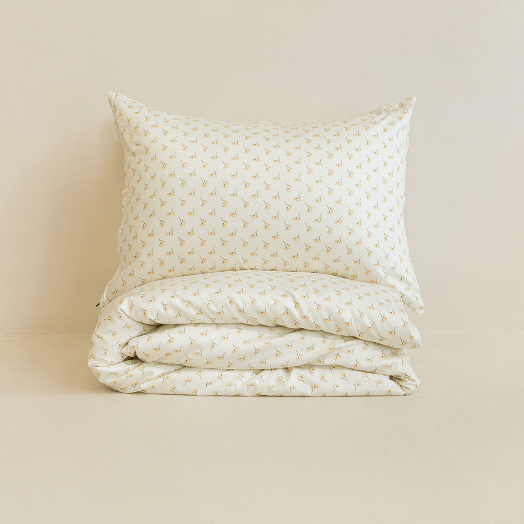 Neatly folded cream floral print quilt cover with one matching pillowcase resting on top
