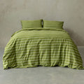 Green striped bedding set on a bed against a plain wall.