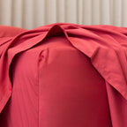 Close-up of red fabric fitted sheet corner on mattress. 