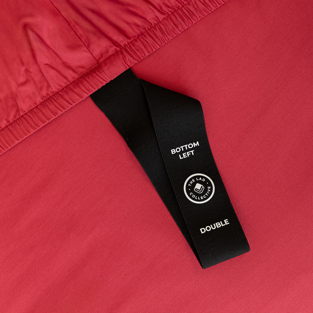 Close-up of a red fabric with a black labelled corner loop strap showing. 