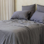Charcoal coloured cooling blanket styled on a bed.