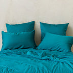 Teal coloured cooling blanket styled on a bed with matching coloured pillowcases.