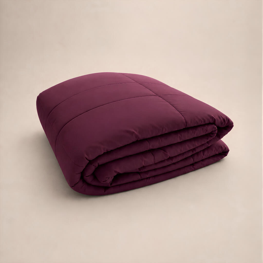 Folded burgundy cooling blanket on a beige background