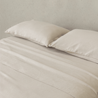 Close-up of beige fitted sheets and matching pillowcases, highlighting the soft brushed texture, warm natural color, and comfortable finish.
