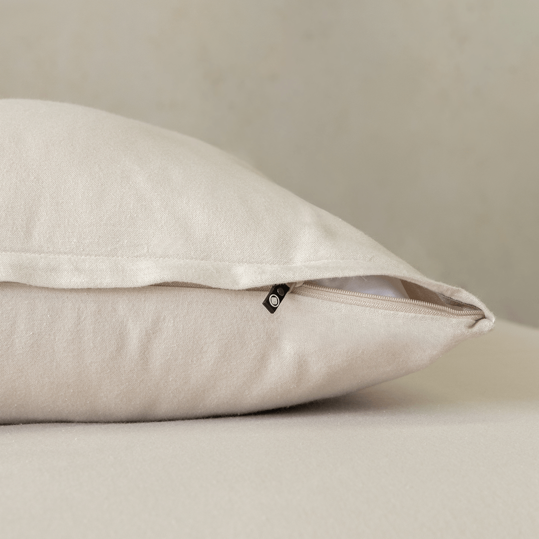Close-up of a beige pillowcase featuring a concealed zipper closure, highlighting the secure fastening detail and soft, warm-toned fabric texture.