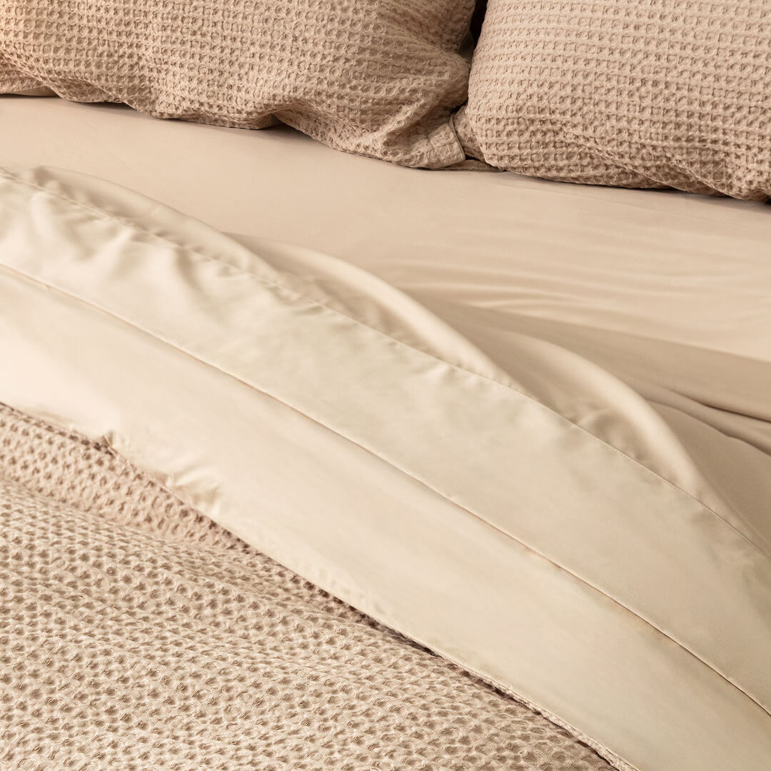 Close-up of beige bedding with textured pillows.