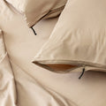 Beige pillows and bedding set with zipper details on a neutral background.