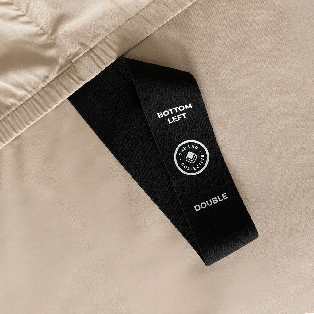 Close-up of a black label on beige fabric with text and a logo.