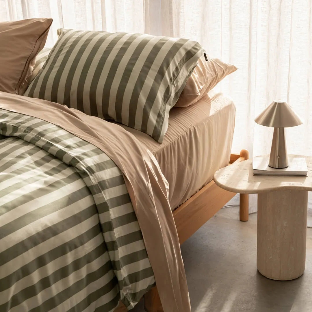 Daintree stripe quilt cover paired with coral bed bedding set, against a beige curtain backdrop. A marble bed side table and lamp featured in the corner.