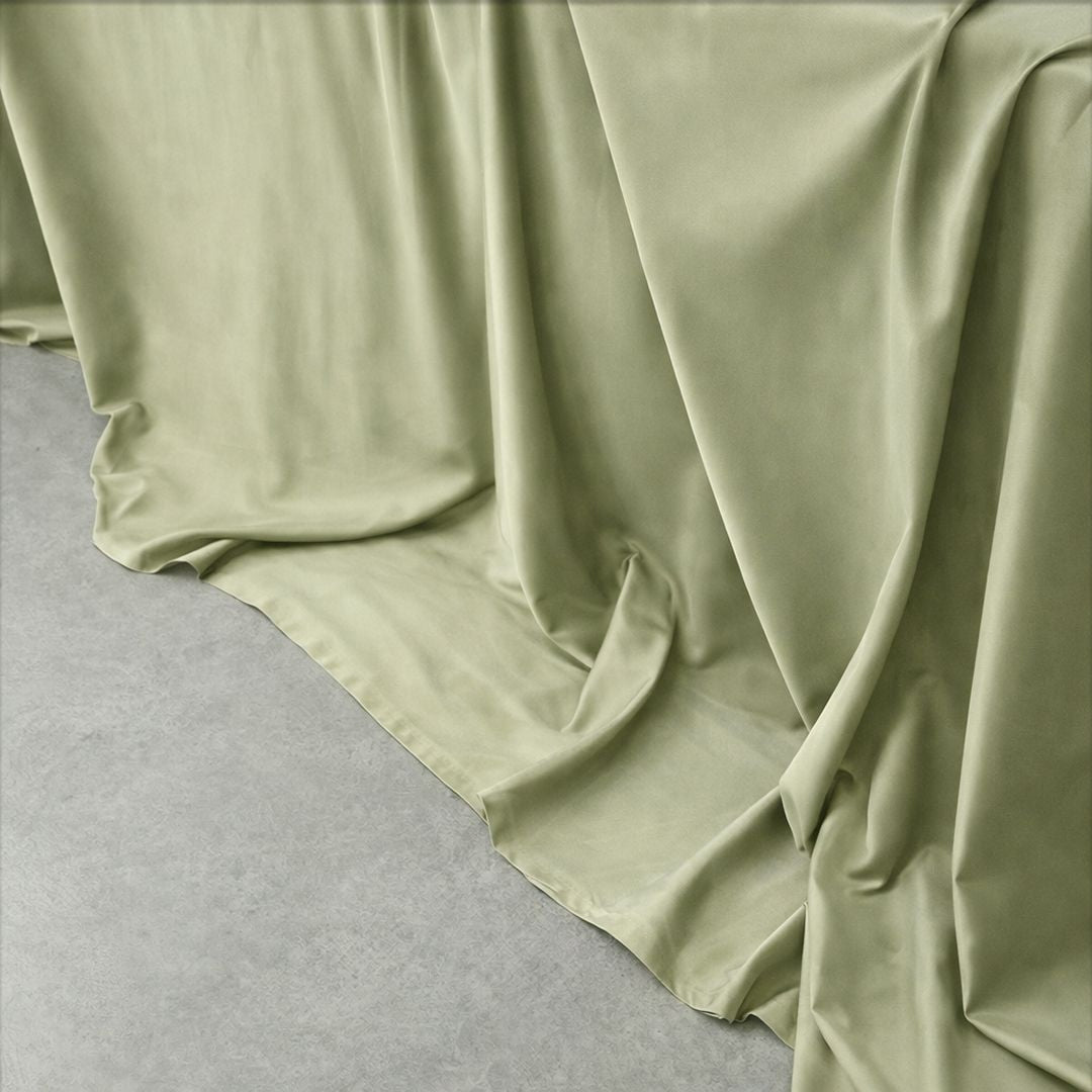 Light green fabric draped over a surface on a grey background.
