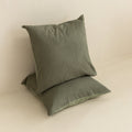 Two green textured European pillows on a beige surface.