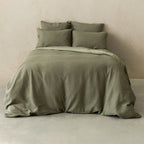 Green textured bedding set on a bed against a beige wall.