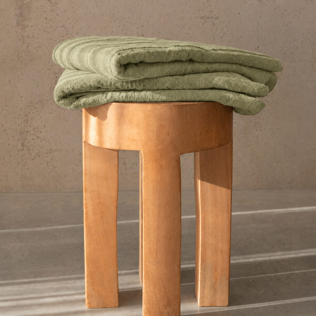 Sage bath towel folded on stool