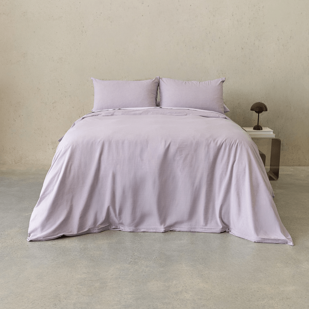 Daylesford lilac quilt cover set styled on a bed with matching pillowcases in a minimalist bedroom.