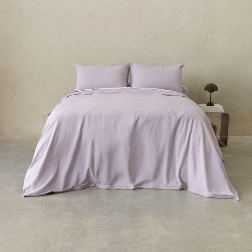Daylesford lilac quilt cover set styled on a bed with matching pillowcases in a minimalist bedroom.