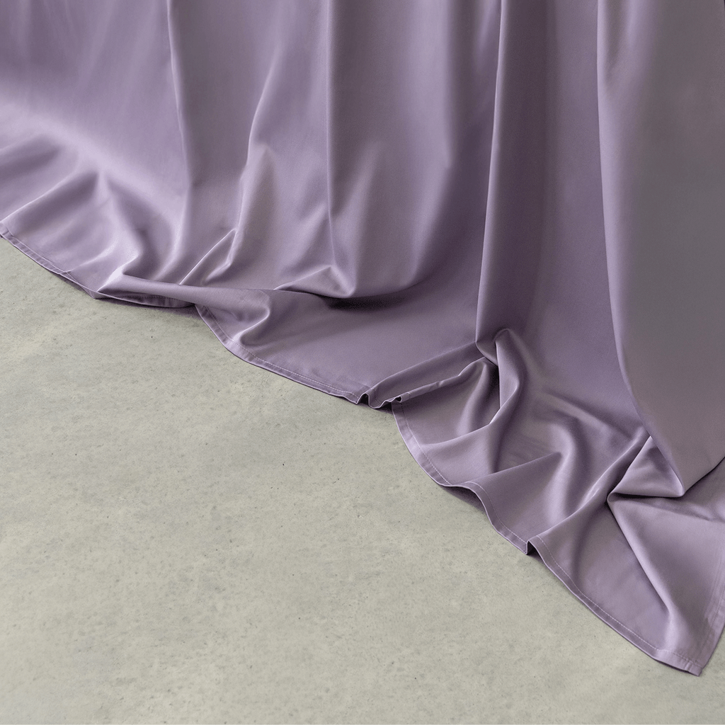 Close-up of the Daylesford quilt draping naturally over the edge of the bed, highlighting the smooth fabric and elegant flow.