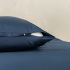 Close-up of a navy blue pillowcase showing a partially open zipper closure revealing white pillow fill